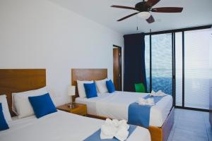 a bedroom with two beds and a ceiling fan at Yuum Ha Boutique Hotel in Río Lagartos