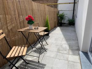 eine Terrasse mit einem Tisch und Stühlen sowie einer Vase aus roten Blumen in der Unterkunft Attractive modern apartment in Brüssel