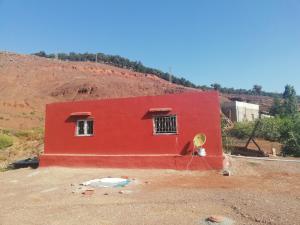een rood huis in het midden van een veld bij Auberge de Tabhirte in Tahla