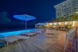 a pool with lounge chairs and umbrellas at night at Condado Ocean Club - Adults Only in San Juan