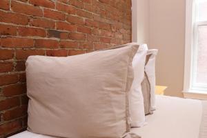 2 cuscini posti su un letto con un muro di mattoni di Charming Studio in Boston Brownstone, #6 a Boston