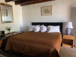 una camera da letto con un grande letto con cuscini bianchi di Cottonwood Court Motel a Santa Fe