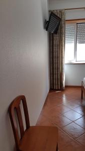 a dining room with a table and a chair and a window at Alojamentos S.José in Atouguia da Baleia