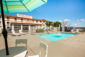 a pool with chairs and an umbrella in front of a hotel at Siegel Select Albuquerque in Albuquerque