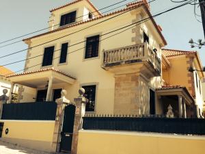 a white house with a balcony on top of it at Villa Sol Mar - Estoril in Estoril