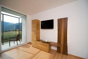 a living room with a tv and a large window at Residence Bar Pizzeria Sylvanerhof in Natz-Schabs