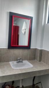 a bathroom with a sink and a red mirror at HOTEL EL EDEN IXTAPALUCA in Ixtapaluca