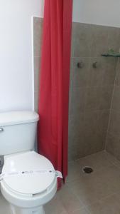 a bathroom with a toilet and a red shower curtain at HOTEL EL EDEN IXTAPALUCA in Ixtapaluca