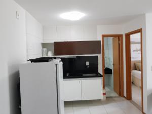 a kitchen with white cabinets and a black counter top at Iloa Residence Resort - Barra de São Miguel in Barra de São Miguel