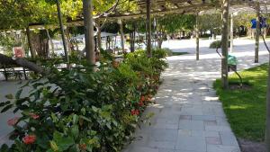 a garden with a bunch of flowers under a pergola at Iloa Residence Resort - Barra de São Miguel in Barra de São Miguel