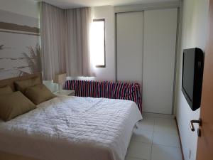 a bedroom with a bed and a flat screen tv at Iloa Residence Resort - Barra de São Miguel in Barra de São Miguel