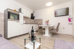 un salon avec une cuisine et une table avec des verres à vin dans l'établissement Apartment Mia, à Trogir