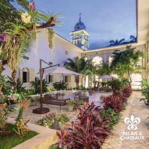 a courtyard with benches and a building with a clock tower at Hotel del Parque in Guayaquil
