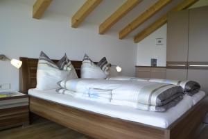 una camera da letto con un grande letto con cuscini bianchi di Oberberghof ad Appiano sulla Strada del Vino