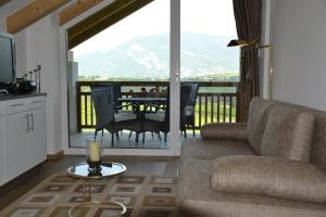 a living room with a couch and a balcony with a table at Oberberghof in Appiano sulla Strada del Vino