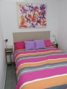 Bett mit bunten Decken und Kissen in einem Zimmer in der Unterkunft Acogedor apartamento con vistas al mar. in Bellreguart