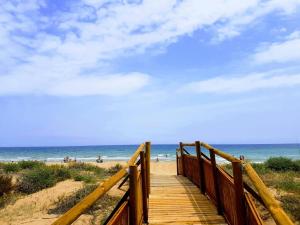 a wooden boardwalk to the beach with people on the beach at Acogedor apartamento con vistas al mar. in Bellreguart
