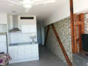 une cuisine avec des placards blancs et un mur en briques dans l'établissement Acogedor apartamento con vistas al mar., à Bellreguart