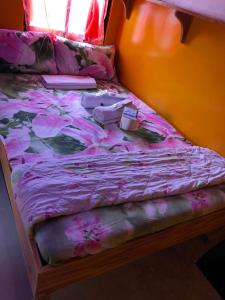 ein Bett mit einer rosa Decke und Schuhen darauf in der Unterkunft ALERTA ROOFTOP LODGE in Magdiwang