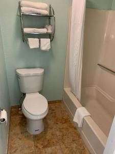 a bathroom with a toilet and a tub and towels at Days Inn by Wyndham Pratt in Pratt