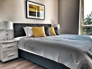 1 dormitorio con 1 cama grande con almohadas amarillas en Luxury 2 Bed 2 Bath Apartment 18 mins from Central London - SLEEPS 6 en Watford