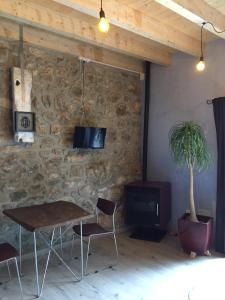 una mesa y sillas en una habitación con una pared de piedra en La Cabaña de Bernardina, en Sotres