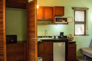 a kitchen with wooden cabinets and a white refrigerator at Cocos Cabañas Playa del Carmen Adults Only in Playa del Carmen