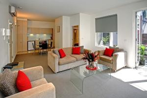 a living room with two couches and a table at Plum Serviced Apartments North Melbourne in Melbourne
