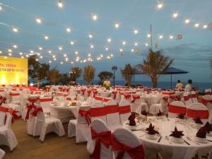 a banquet hall with white tables and red bows at Ly Son Pearl Island Hotel & Resort in Ly Son