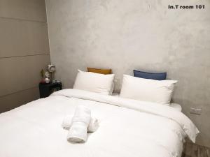 a bed with white sheets and towels on it at In.T in Tainan