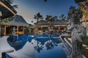 a resort pool with a statue in front of a building at LGood Lembongan Island Villas in Nusa Lembongan