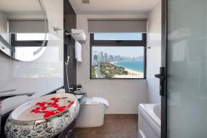 a bathroom with a sink and a bath tub with a window at Ruby Hotel in Nha Trang