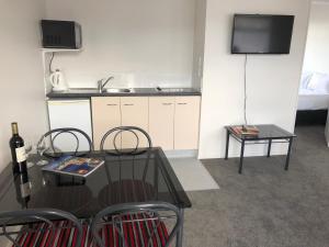 a kitchen with a table and chairs and a television at Ambassador Motor Inn in Tauranga