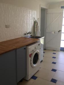 a kitchen with a washing machine and a sink at Breakaway Cottage in Tumbarumba