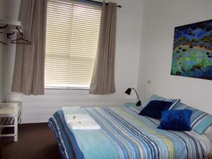 una camera da letto con un letto con cuscini blu e una finestra di Breakaway Cottage a Tumbarumba