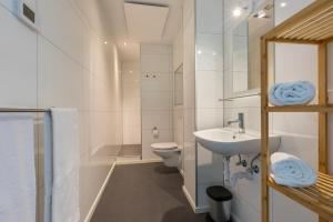 a white bathroom with a sink and a toilet at Welcome in - Vakantiehuis 6 en 12 personen, Vroondijk in Vrouwenpolder in Vrouwenpolder