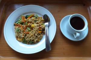 un plato de comida con una taza de café y un tazón de fideos en Kangkung Cottages, en Jasri