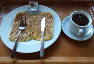 a white plate with toast and a cup of coffee at Kangkung Cottages in Jasri