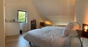a bedroom with a white bed and a window at Ferias - cosy house in Bruges