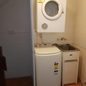 een kleine keuken met een wastafel en een wasmachine bij Coral Sea Villas in Port Douglas