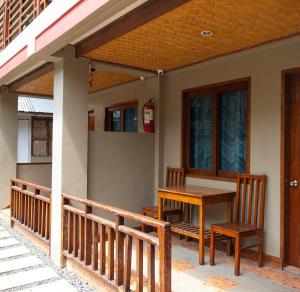 a porch with a wooden table and chairs on a house at Inngo Tourist Inn in El Nido