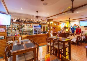a restaurant with tables and chairs and a bar at Patong Karlssons Hotel in Patong Beach
