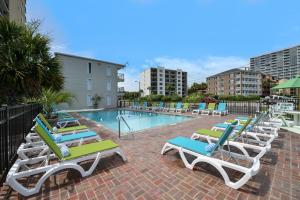 a row of lounge chairs and a swimming pool at The Mermaid Inn in Myrtle Beach