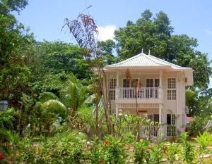 a white house with a balcony in a garden at Bord Mer Villa in Beau Vallon