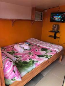 Una cama con flores rosas en una habitación en ALERTA ROOFTOP LODGE, en Magdiwang