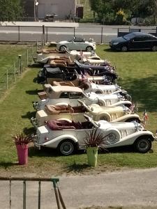 a row of white cars parked in a field at HÔTEL Le 6 3 Resto Home Petit Hôtel de Charme in Port-en-Bessin-Huppain