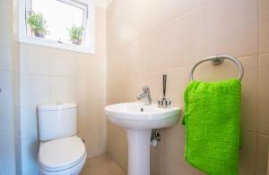 a bathroom with a toilet and a sink and a green towel at Nissi Golden Sand lovely one bedroom apartment with spacious terrace and free parking in Ayia Napa