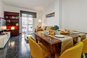 sala de estar con mesa de madera y sillas amarillas en Family Apartment, en Málaga