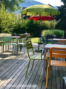 een groep tafels en stoelen met een paraplu bij Hotel Katharinenhof STANDARD in Dornbirn