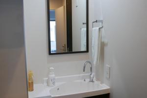 a bathroom with a white sink and a mirror at Tokyo Sakurako Hatchobori in Tokyo